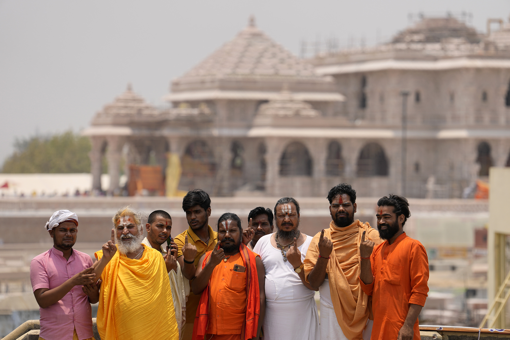 Indian Hindu holy men who voted in the fifth round of multi-phase national elections pose for photographs in front of the temple of Hindu god Ram in Ayodhya, India, on May 20.