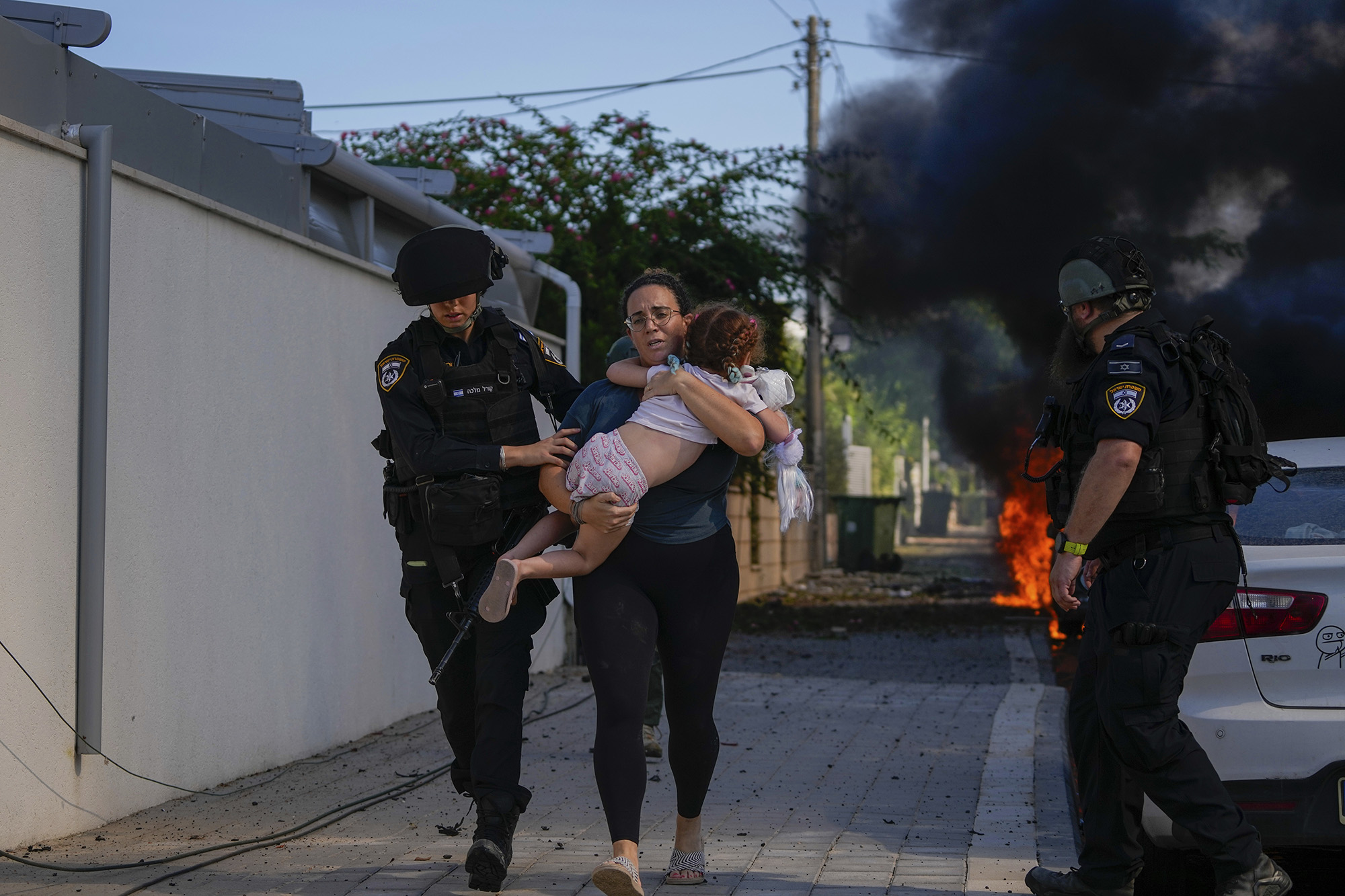 Israeli police officers evacuate a woman and a child from a site hit by a rocket fired from Gaza, in Ashkelon, southern Israel, on October 7.