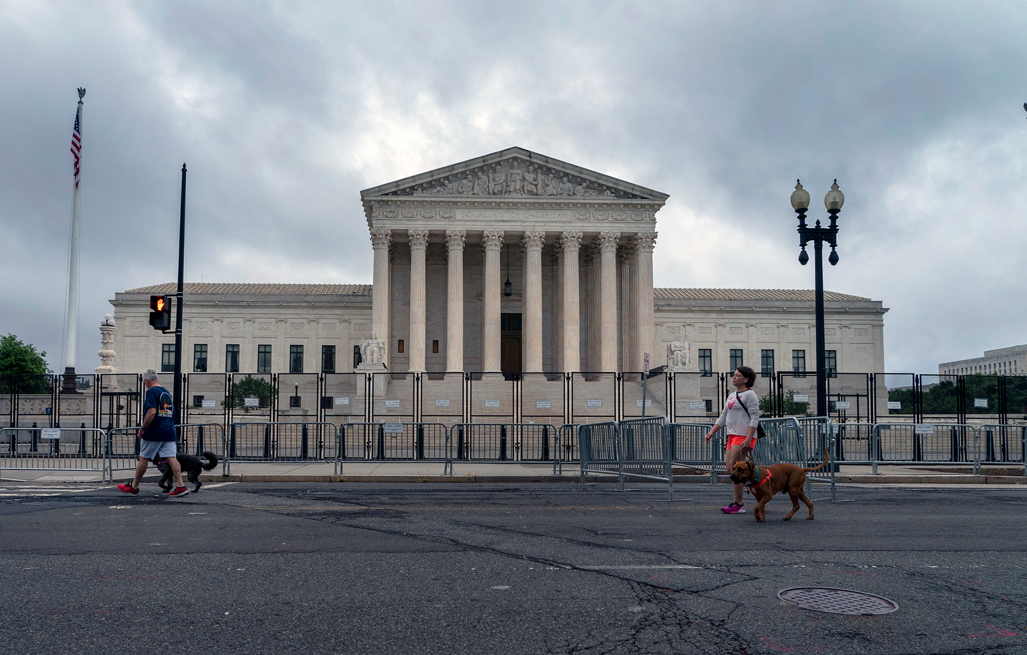 People walk dogs past anti-scaling fencing erected around the U.S. Supreme Court building in Washington, on Thursday, June 23.