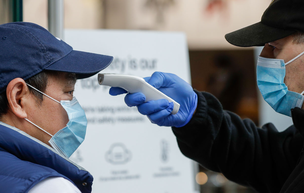 A security guard takes the temperature of a customer at a shopping precinct in Sydney, Australia on January 3.