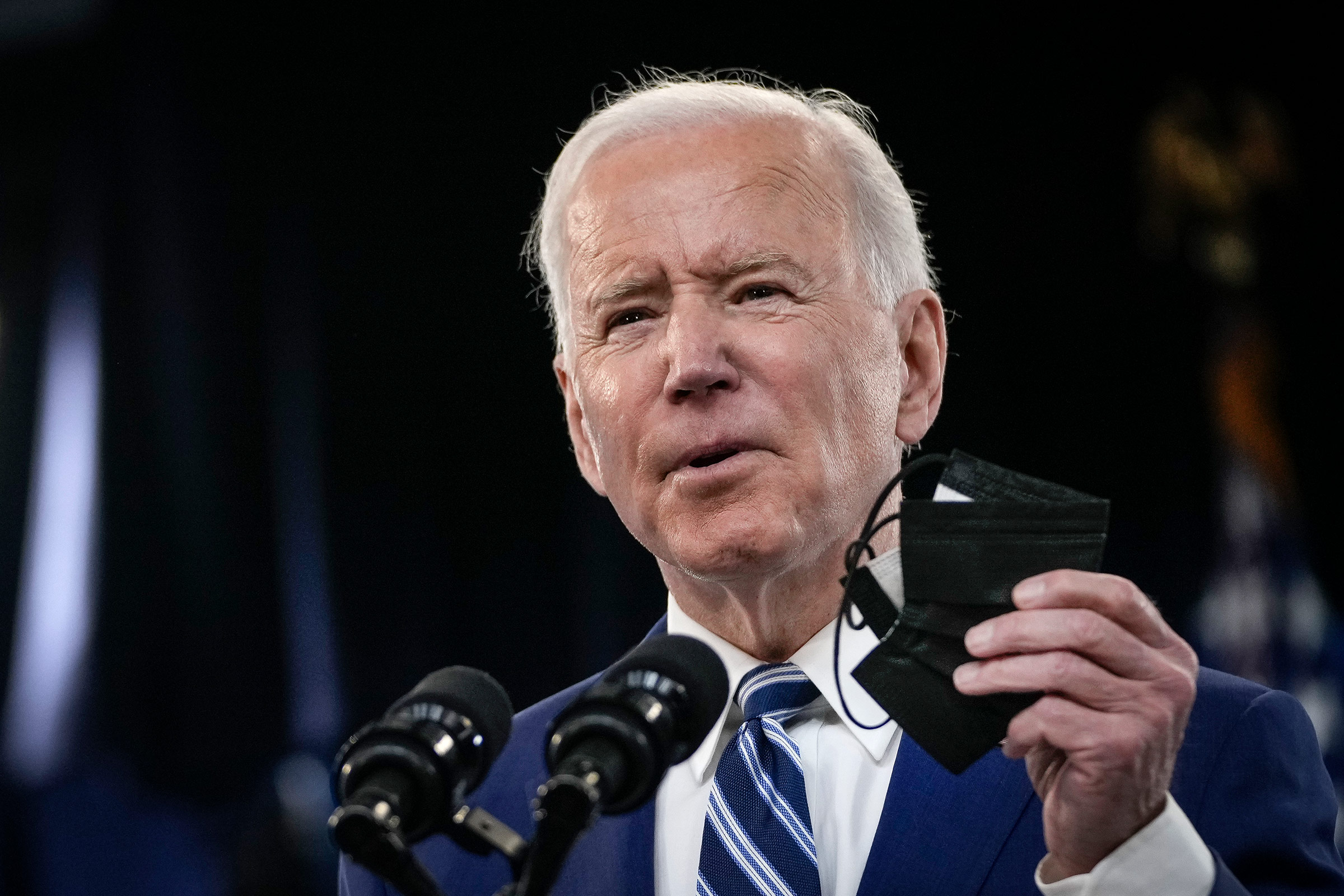 President Joe Biden holds up a face mask as he delivers remarks at the White House on March 29, in Washington, DC. 
