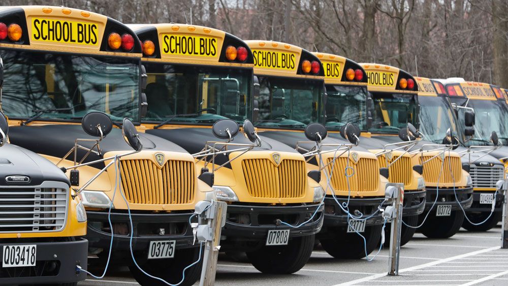 A row of school buses rests in a parking lot, on Tuesday, April 7, in Cleveland Heights, Ohio.