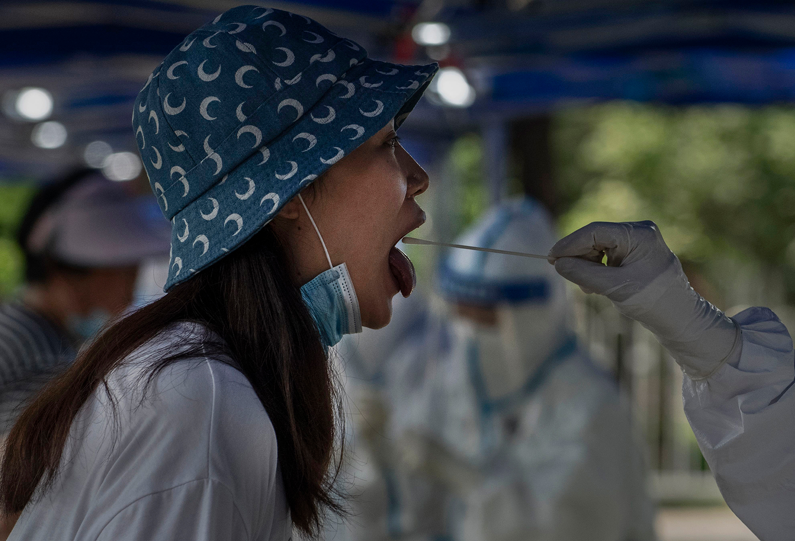 A Chinese epidemic control worker performs a nucleic acid swab test for Covid-19 on a woman at a government testing site on June 22, in Beijing.