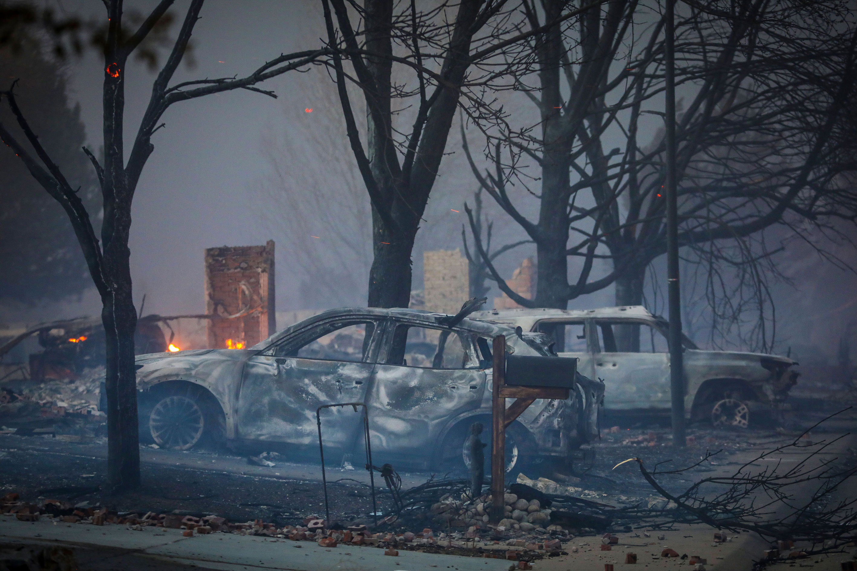 Burnt out vehicles sit amidst the smoke and haze after a fast moving wildfire swept through the area in the Centennial Heights neighborhood of Louisville, Colorado on December 30.