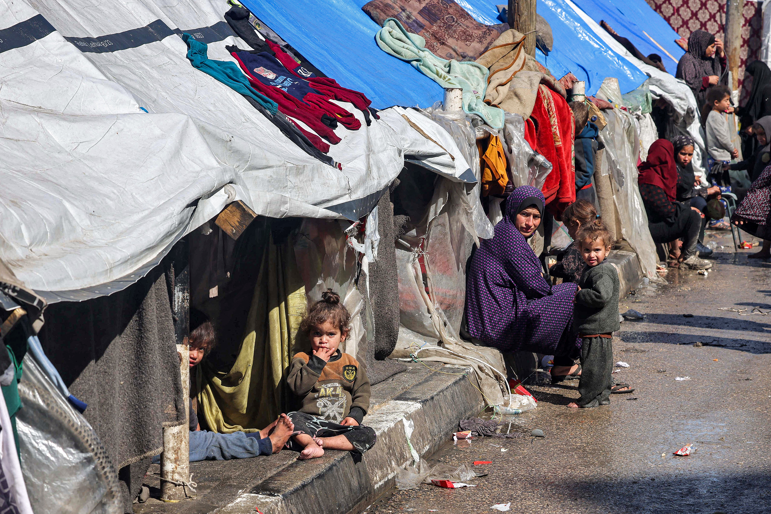 A woman and children sit outside tents sheltering displaced Palestinians in Rafah, Gaza, on February 8. 