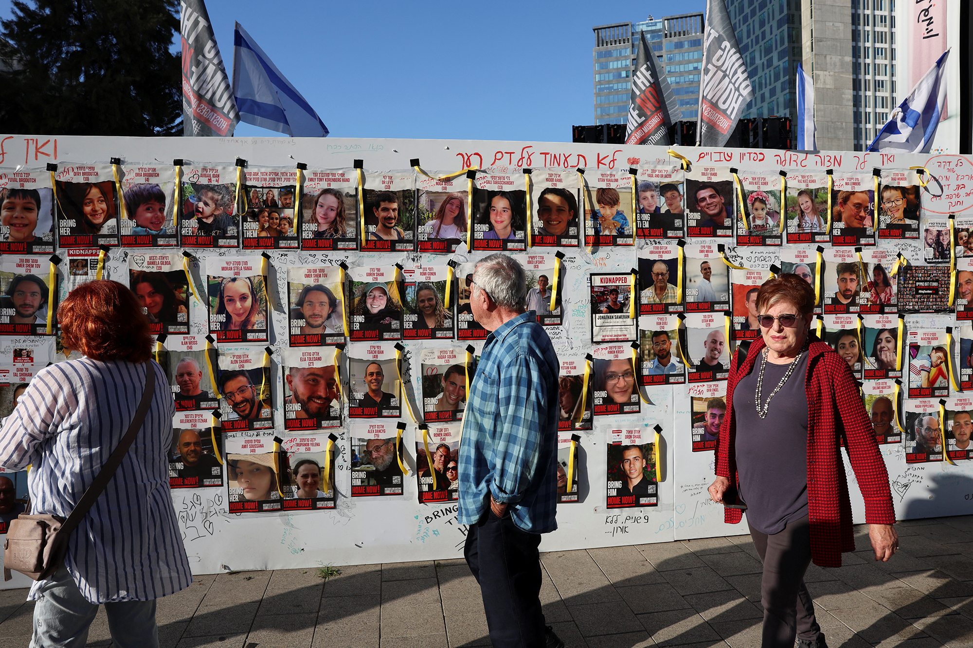 People walk past a wall with posters showing missing people in Tel Aviv, Israel, on November 30. 