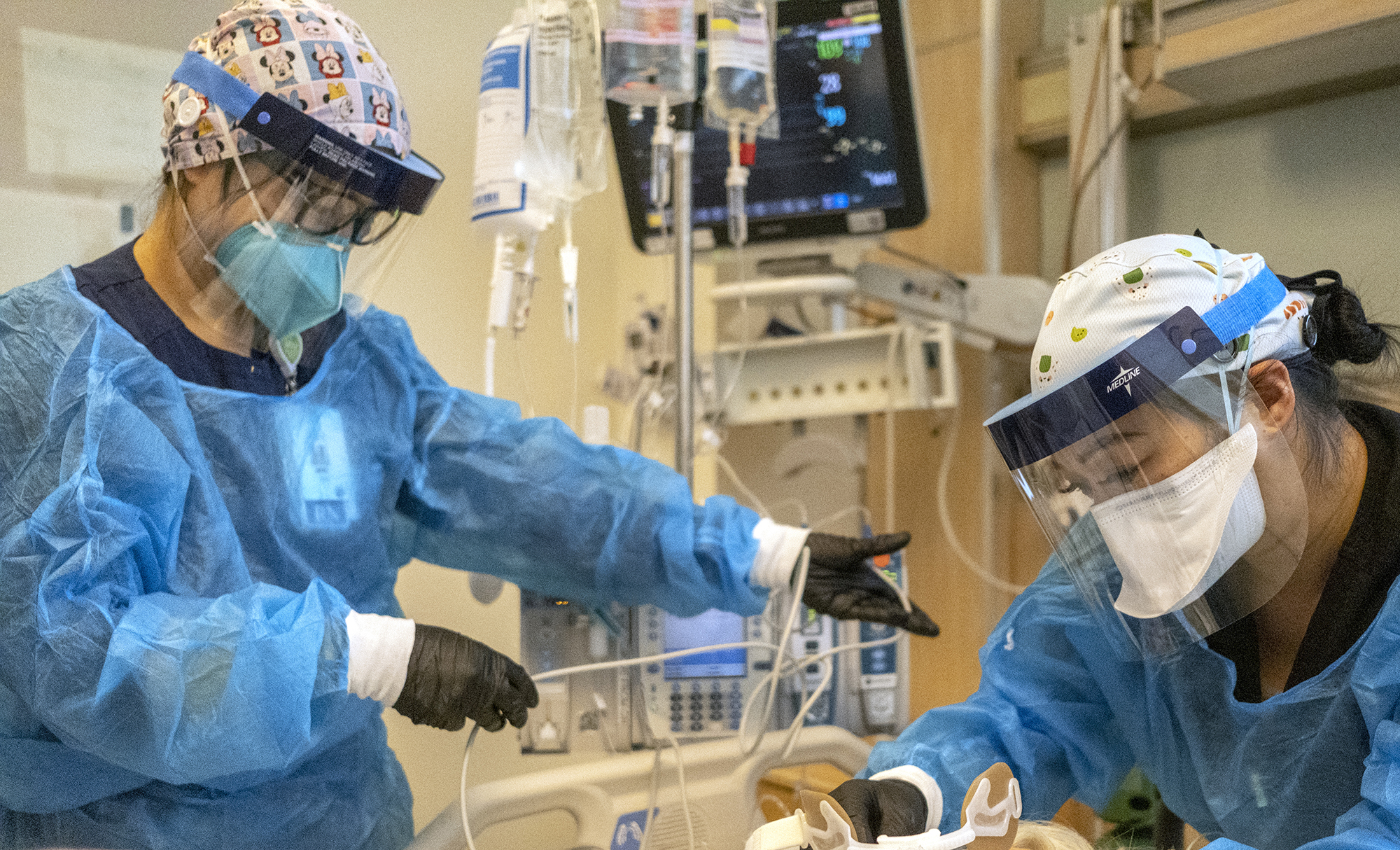 Registered nurse Akiko Gordon, left, and Therapist Janssen Redondo, right, work inside the ICU with a covid-19 positive patient at Martin Luther King Jr Community Hospital.  (MLKCH) on Friday, December 31, 2021 in Los Angeles, CA. 