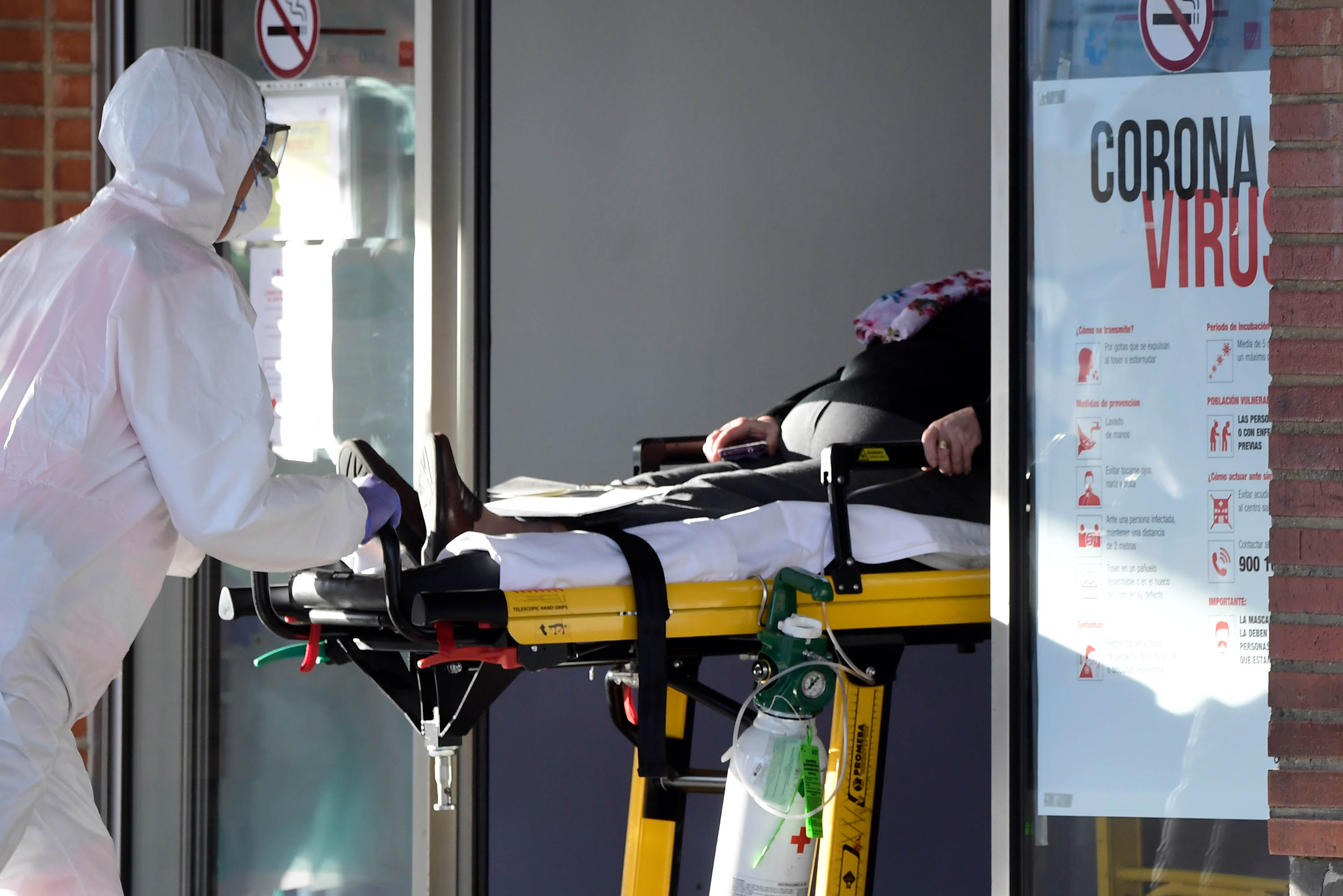 A health worker wearing personal protective equipment pushes a patient on a stretcher at a hospital in Leganes, Spain, on March 26. JAVIER SORIANO/AFP via Getty Images)