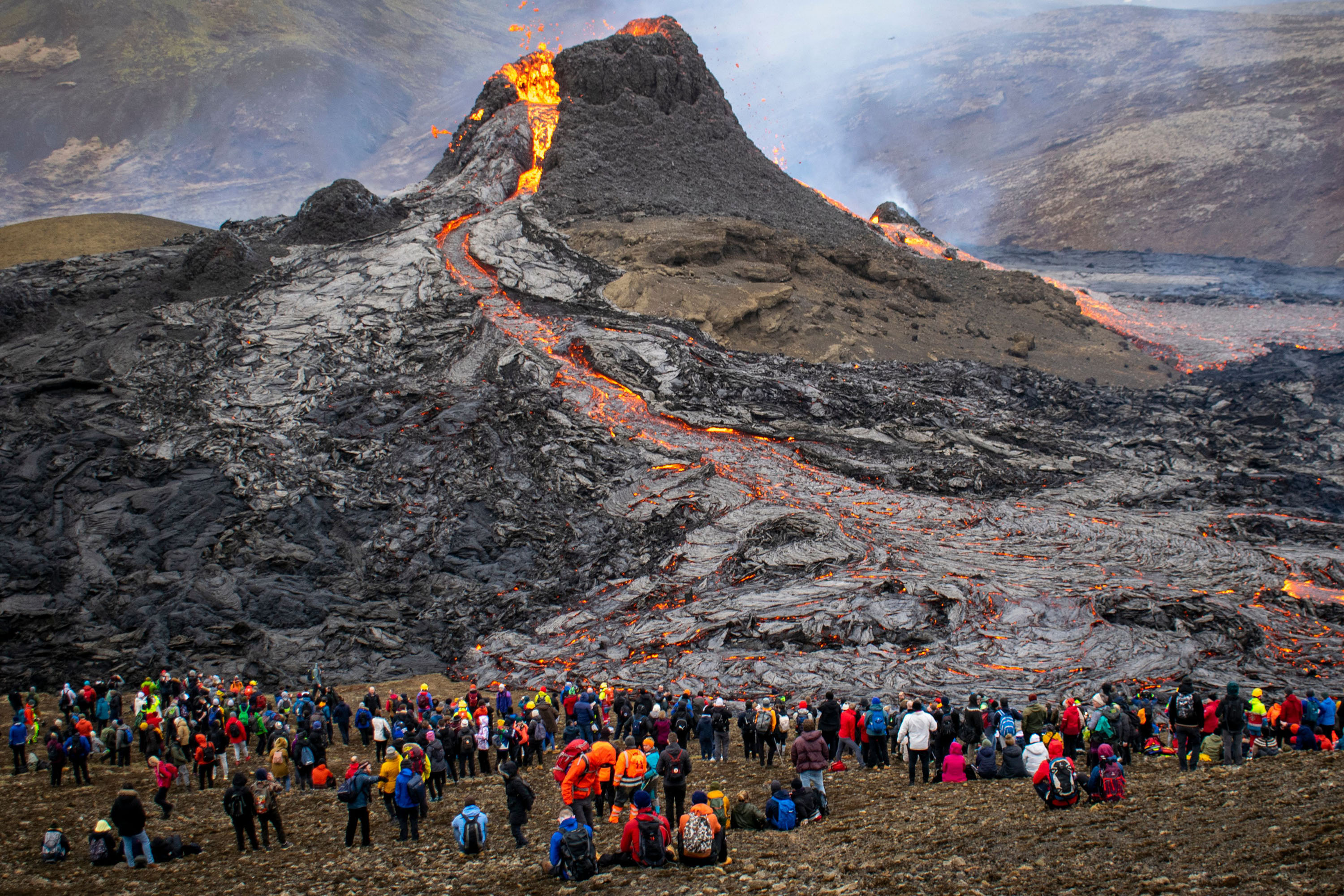People watch lava flow during an eruption of Iceland's Fagradalsfjall volcano on March 21, 2021. 
