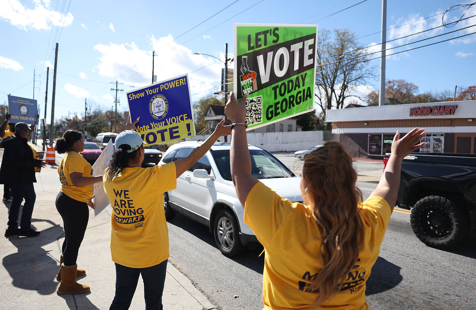 Volunteers hold signs to encourage people to early vote outside of a polling station on November 27 in Atlanta. 