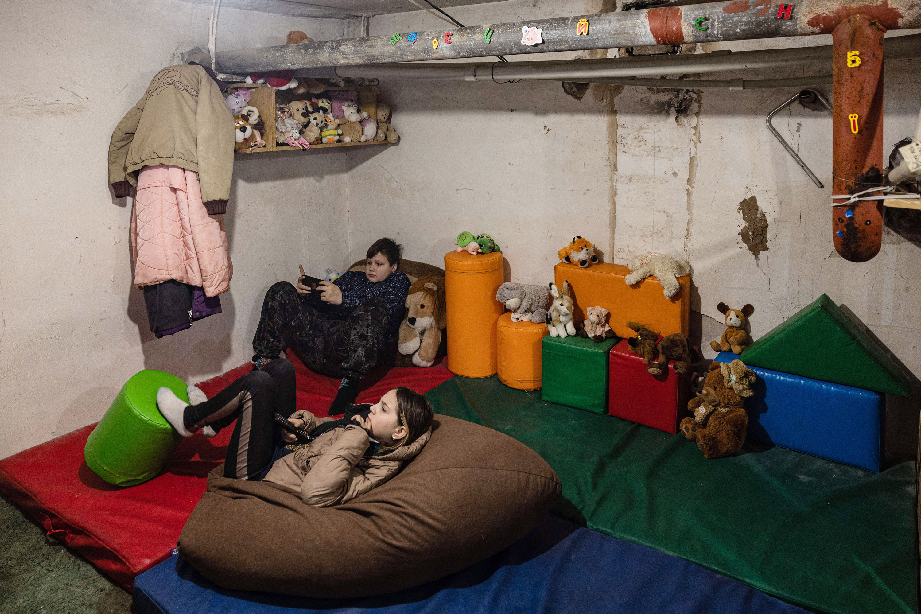 Children watch television in a basement where neighbors gather to seek protection from shelling by Russian forces December 22 in the city of Bakhmut. 