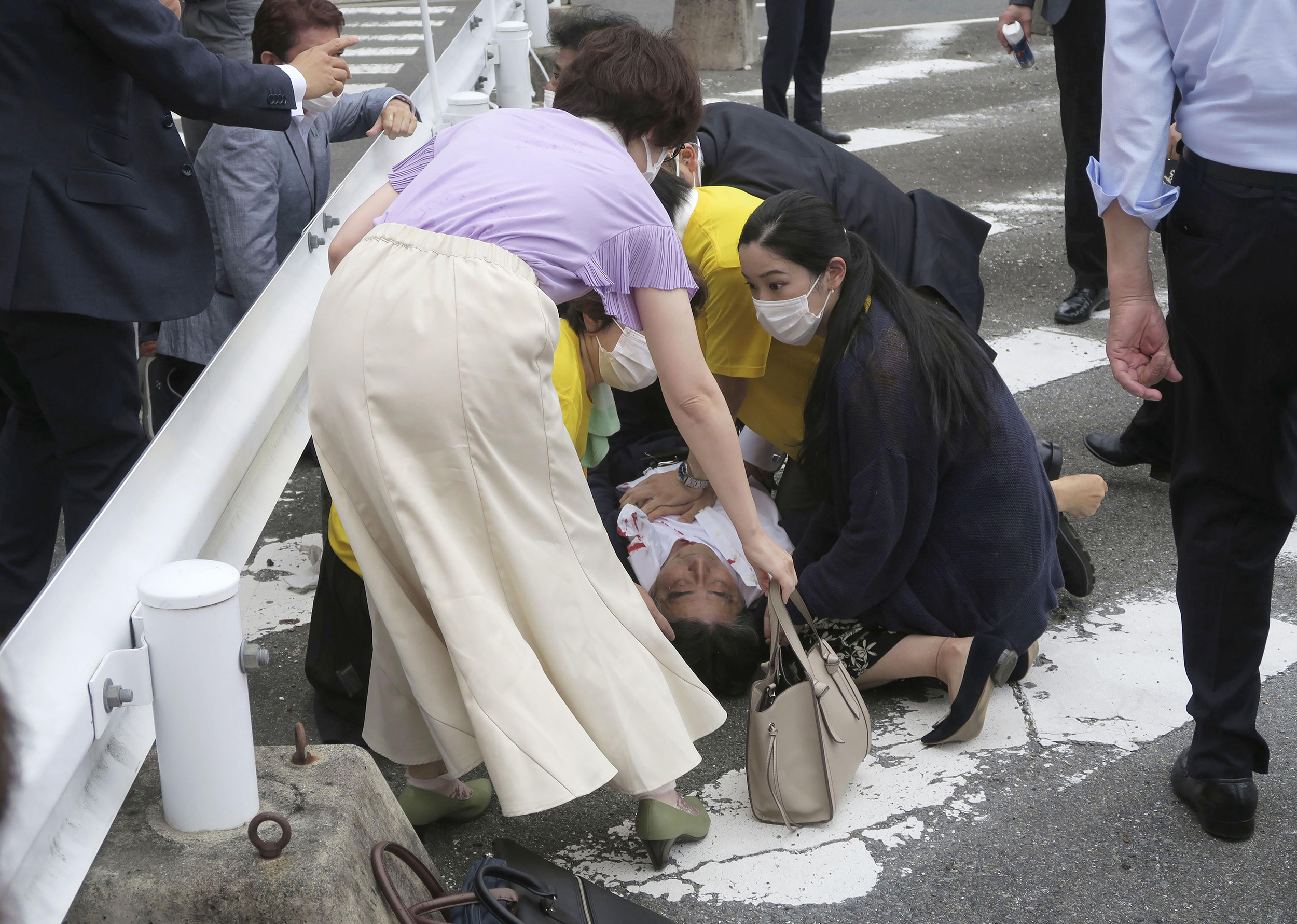 Japan's former Prime Minister Shinzo Abe, center, lies on the ground having been shot in Nara, Japan, on July 8.