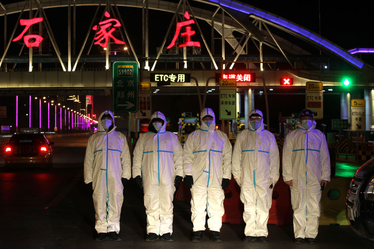 Police officers wearing protective suits stand guard at the entrance of an expressway on January 6 in Shijiazhuang, Hebei Province, China.