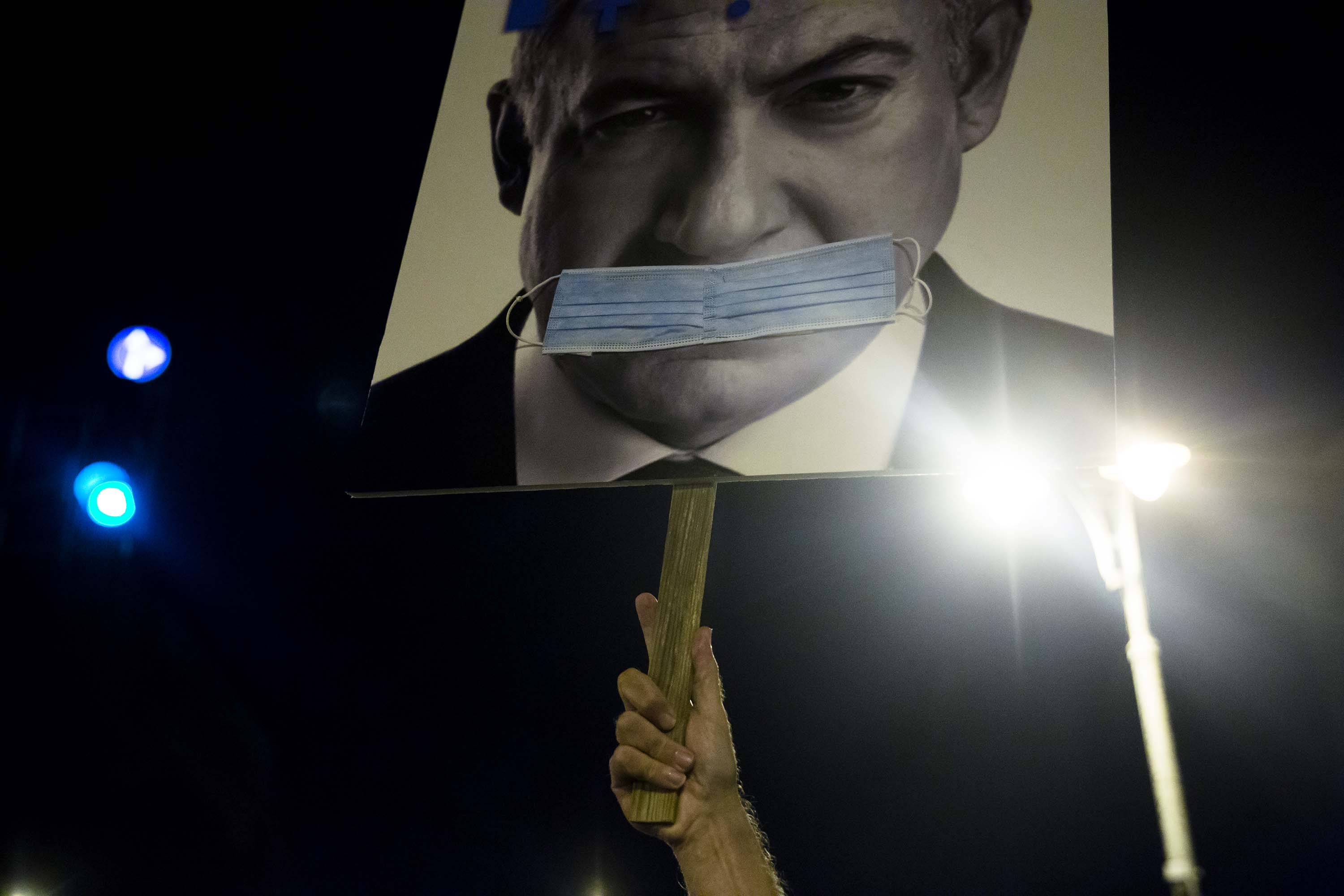 A protester holds a sign depicting Israeli Prime Minister Benjamin Netanyahu with a face mask during a demonstration in Jerusalem on September 20.