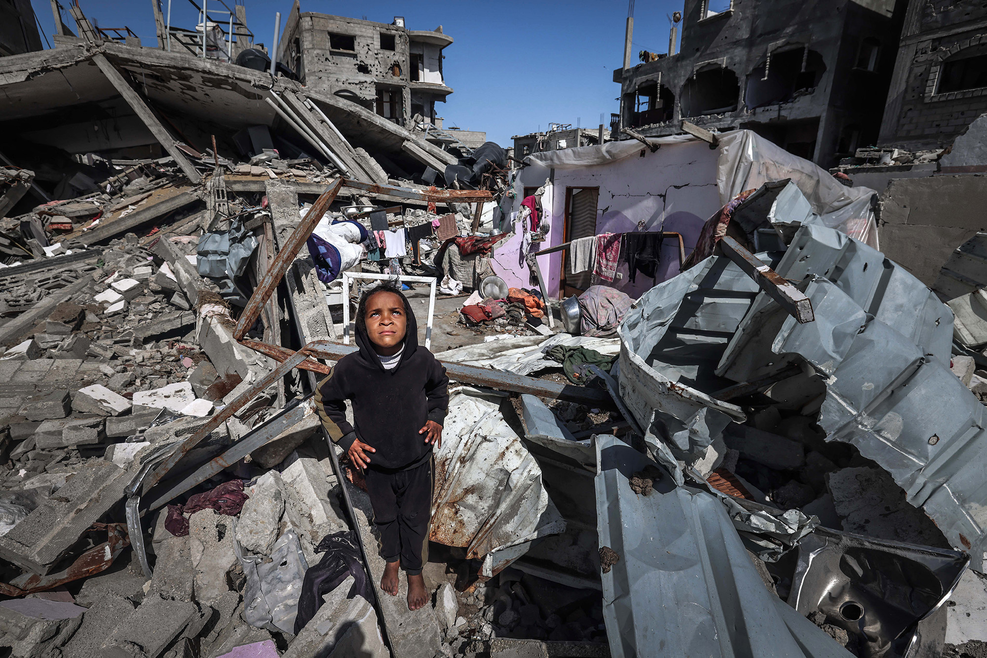 A Palestinian girl looks up to watch a military drone as she stands on the rubble of destroyed houses in the Rafah refugee camp in Gaza on March 21.