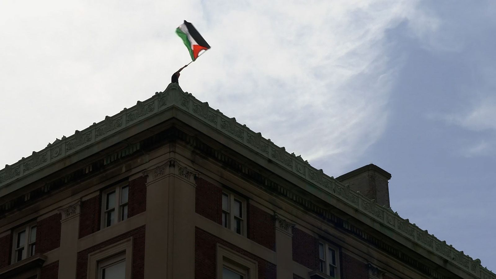 A protester waves a Palestinian flag from the roof of Hamilton Hall at Columbia University in New York on Tuesday.