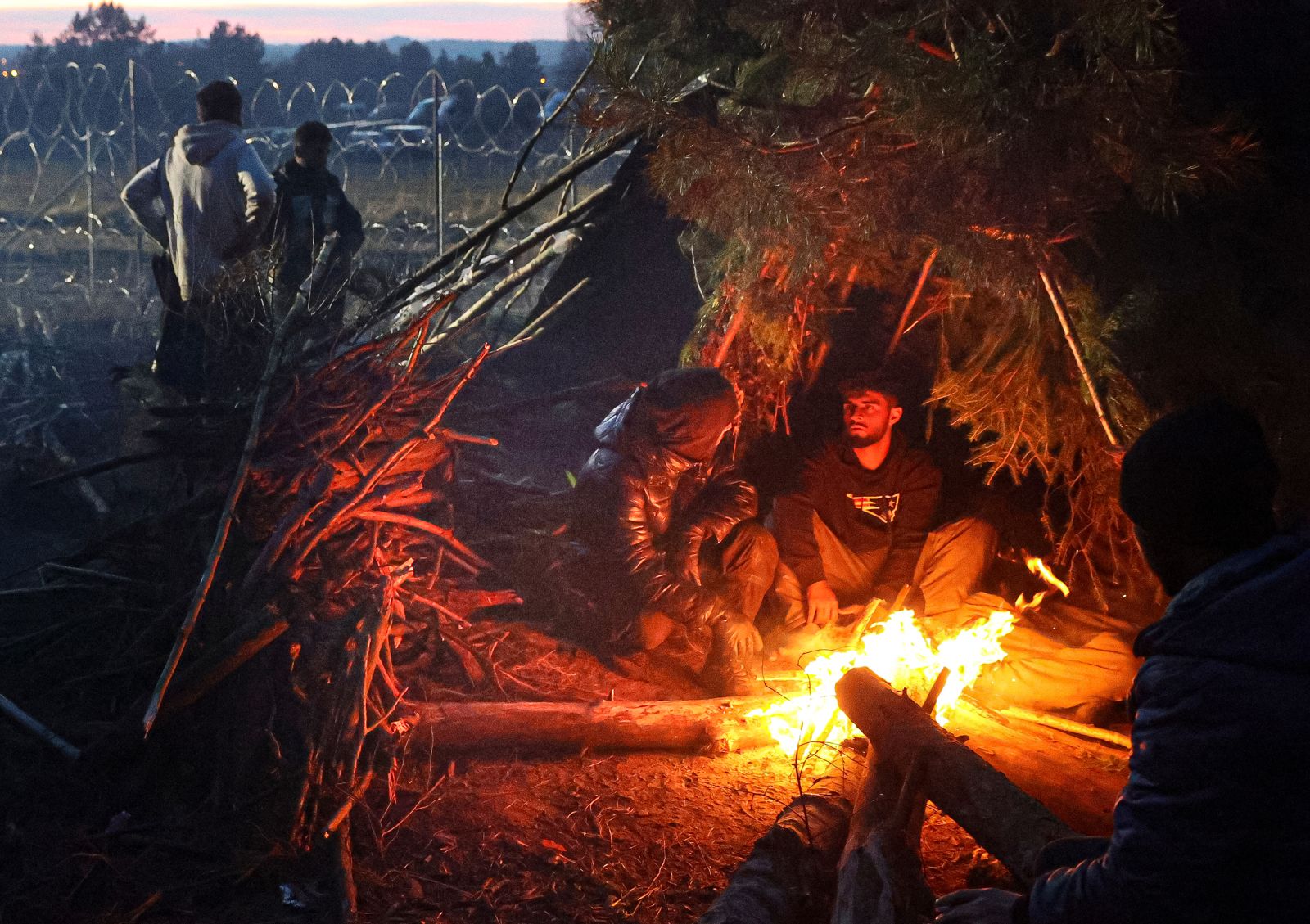 Migrants sit by a fire near the Poland-Belarus border on Wednesday, November 10. 