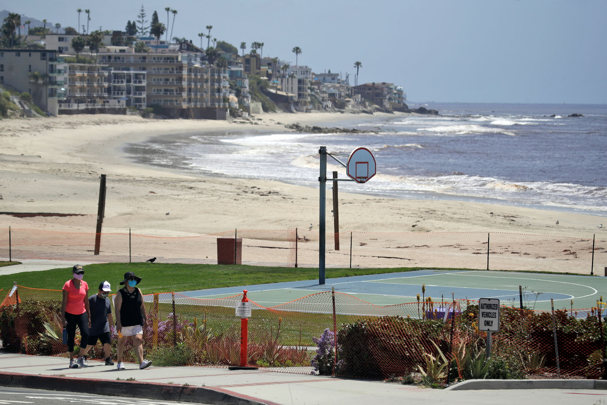 People walk past a closed off beach on May 3, in Laguna Beach, Calif.