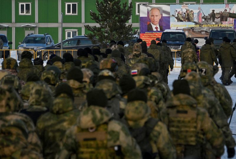 Russian reservists recruited during a partial mobilization of troops walk toward a banner with a portrait of Russian President Vladimir Putin during a ceremony before their departure in Omsk, Russia, on January 6.