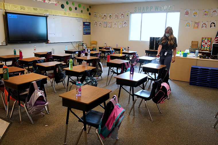 A teacher disinfects desks in a classroom at a public charter school in Provo, Utah, on Thursday, Aug. 20.
