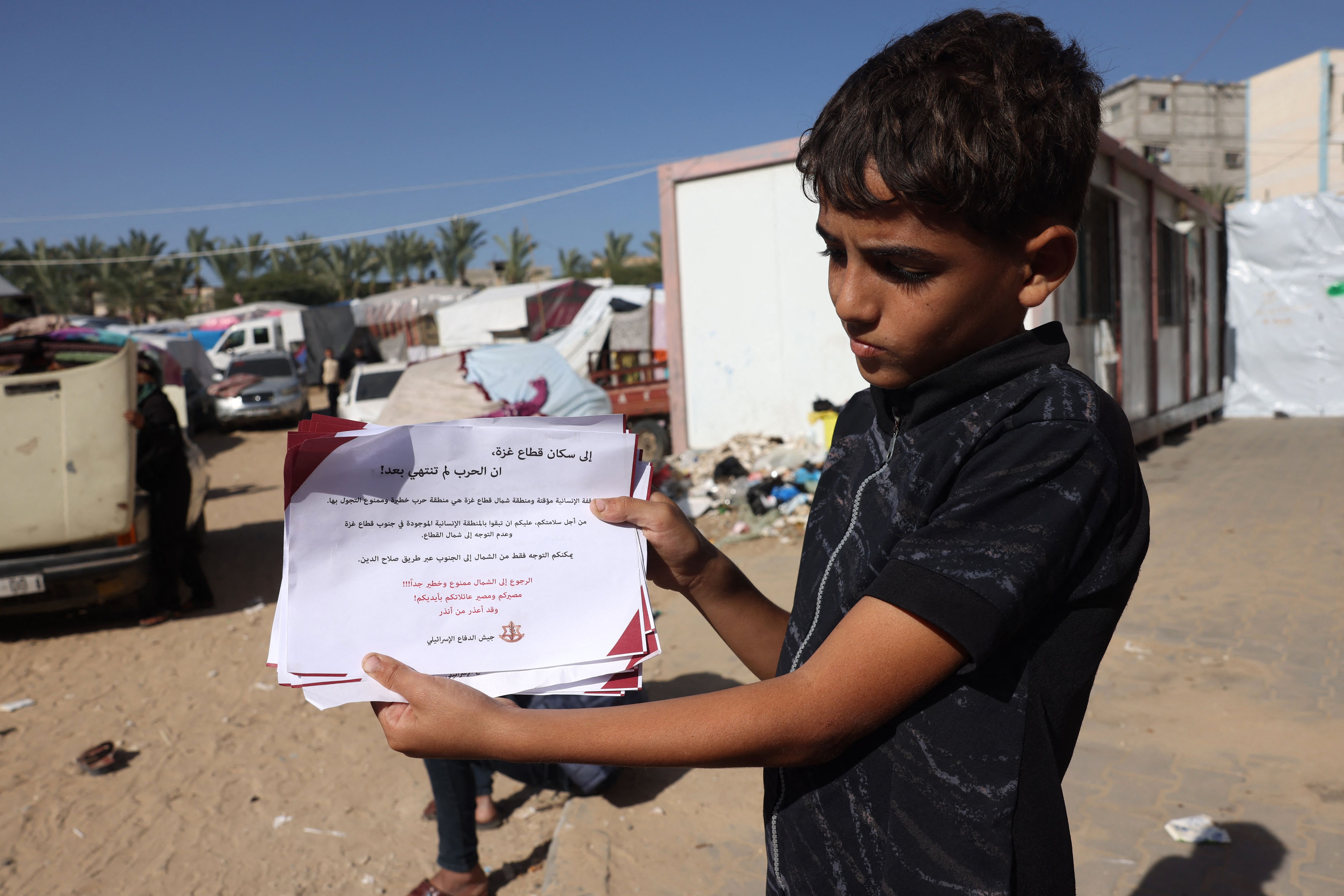 A Palestinian boy carries an Israeli flyer, warning citizens of Gaza not to return to the north, in Khan Younis, southern Gaza, on November 24.