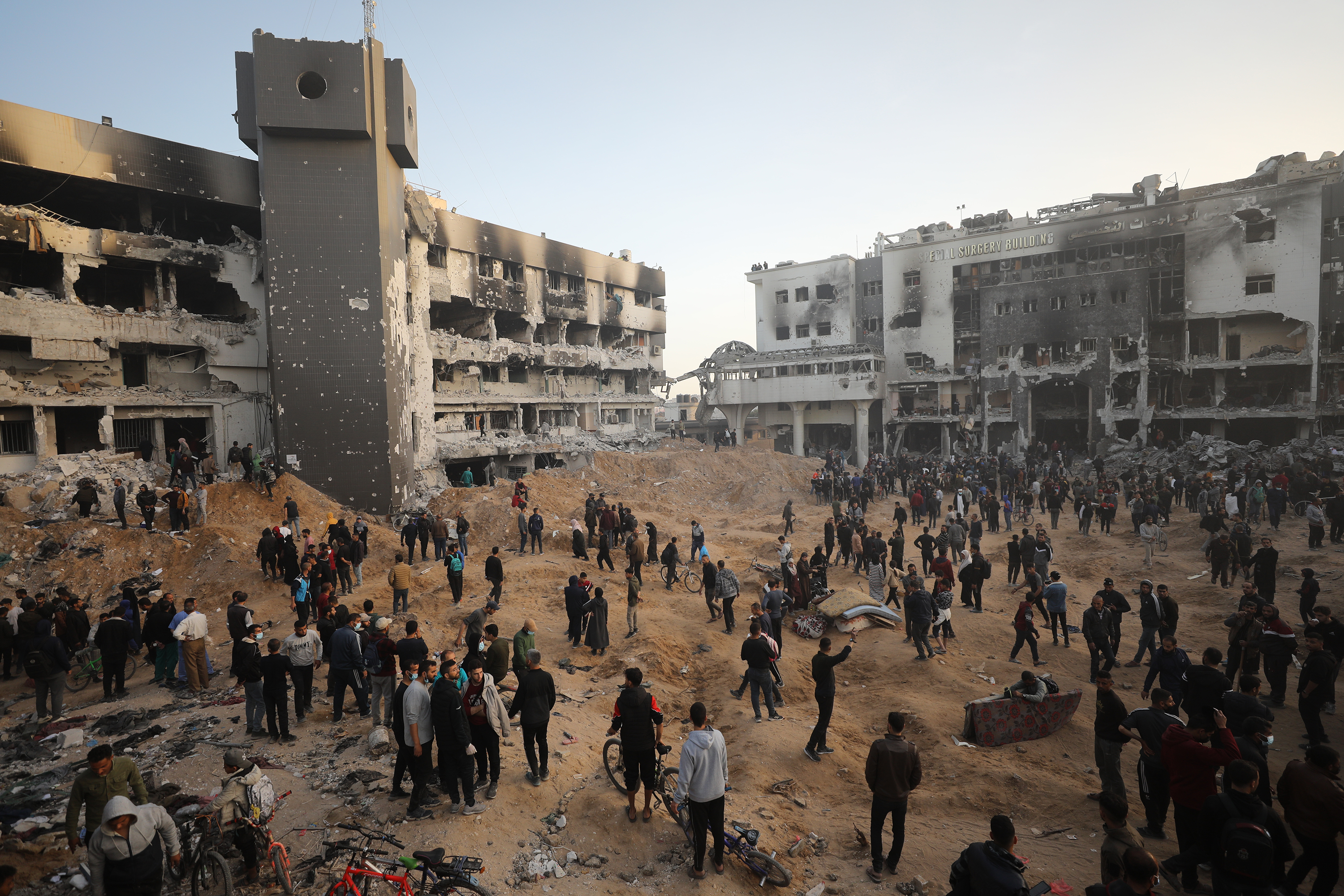 Palestinians gather around the destroyed Al-Shifa hospital.