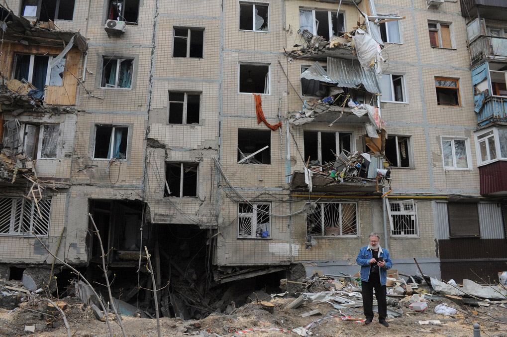 A man stands next to an apartment building damaged by shelling in Kharkiv, on Sunday.