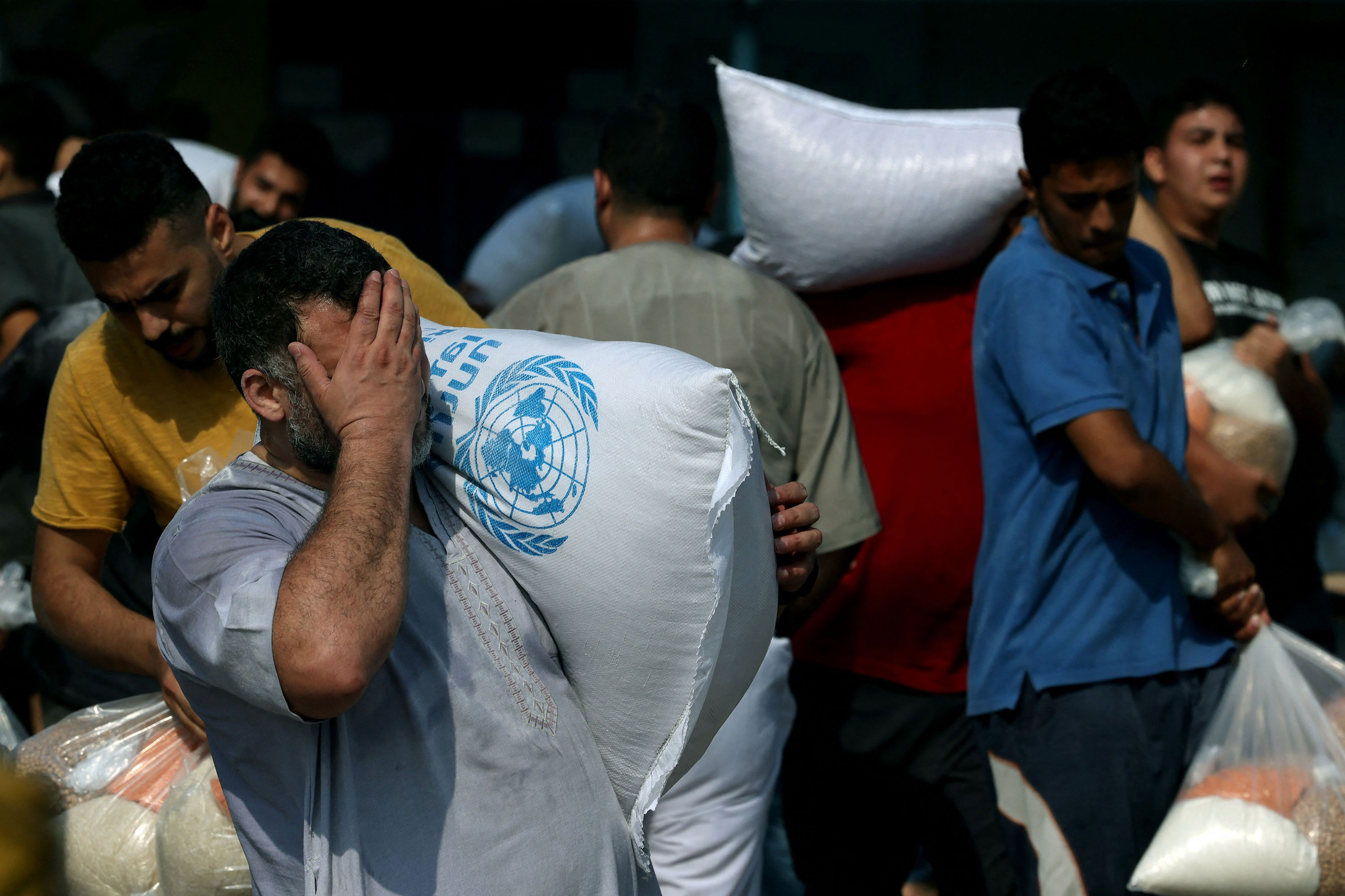 Palestinians collect bags of dried pulses from a UN-run aid supply center in Deir al-Balah, Gaza, on October 28. 