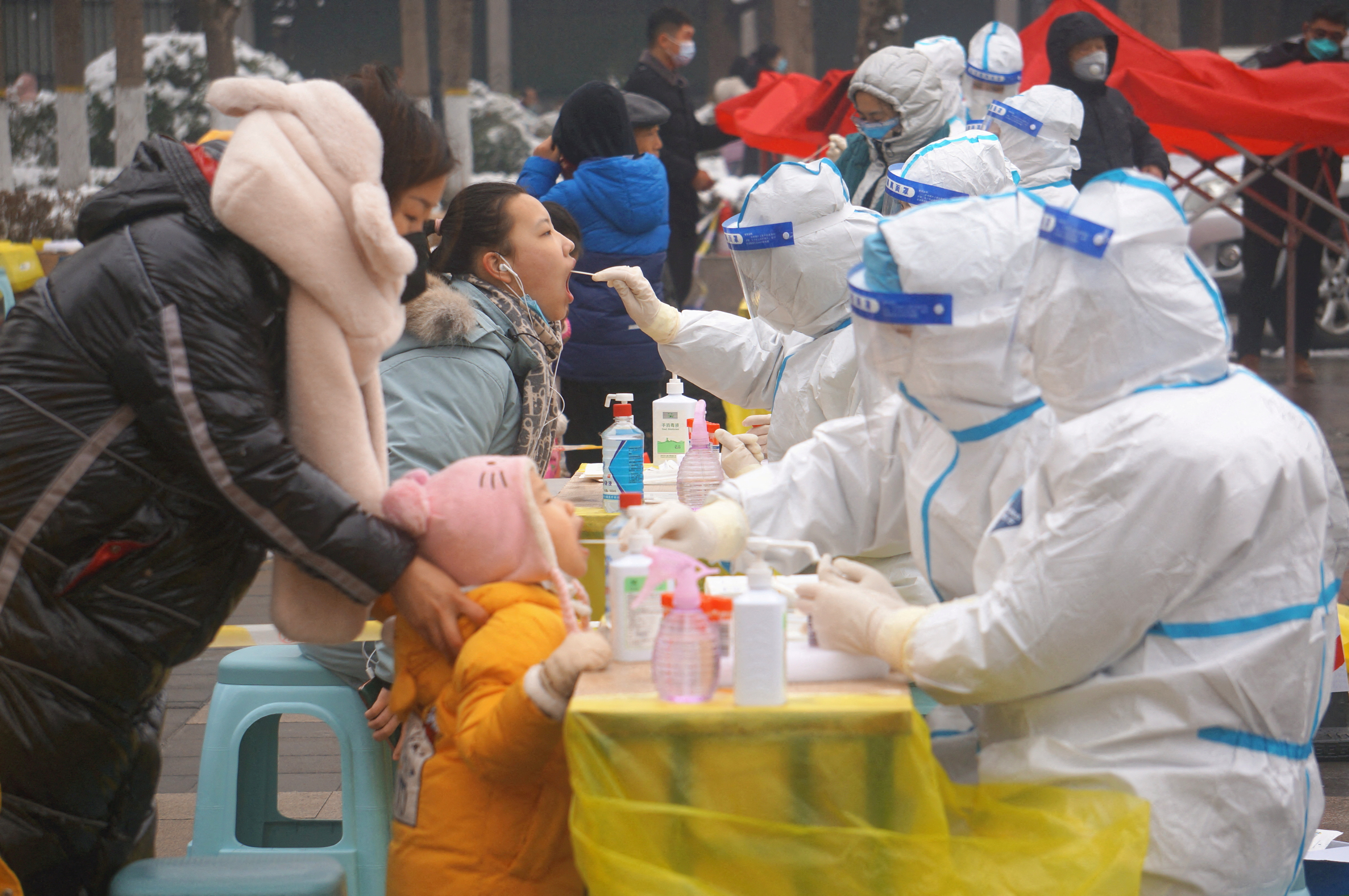 Medical workers in protective suits collect swabs from residents during a citywide nucleic acid testing following cases of the coronavirus disease (COVID-19) in Zhengzhou, Henan province, China, January 5, 2022.  