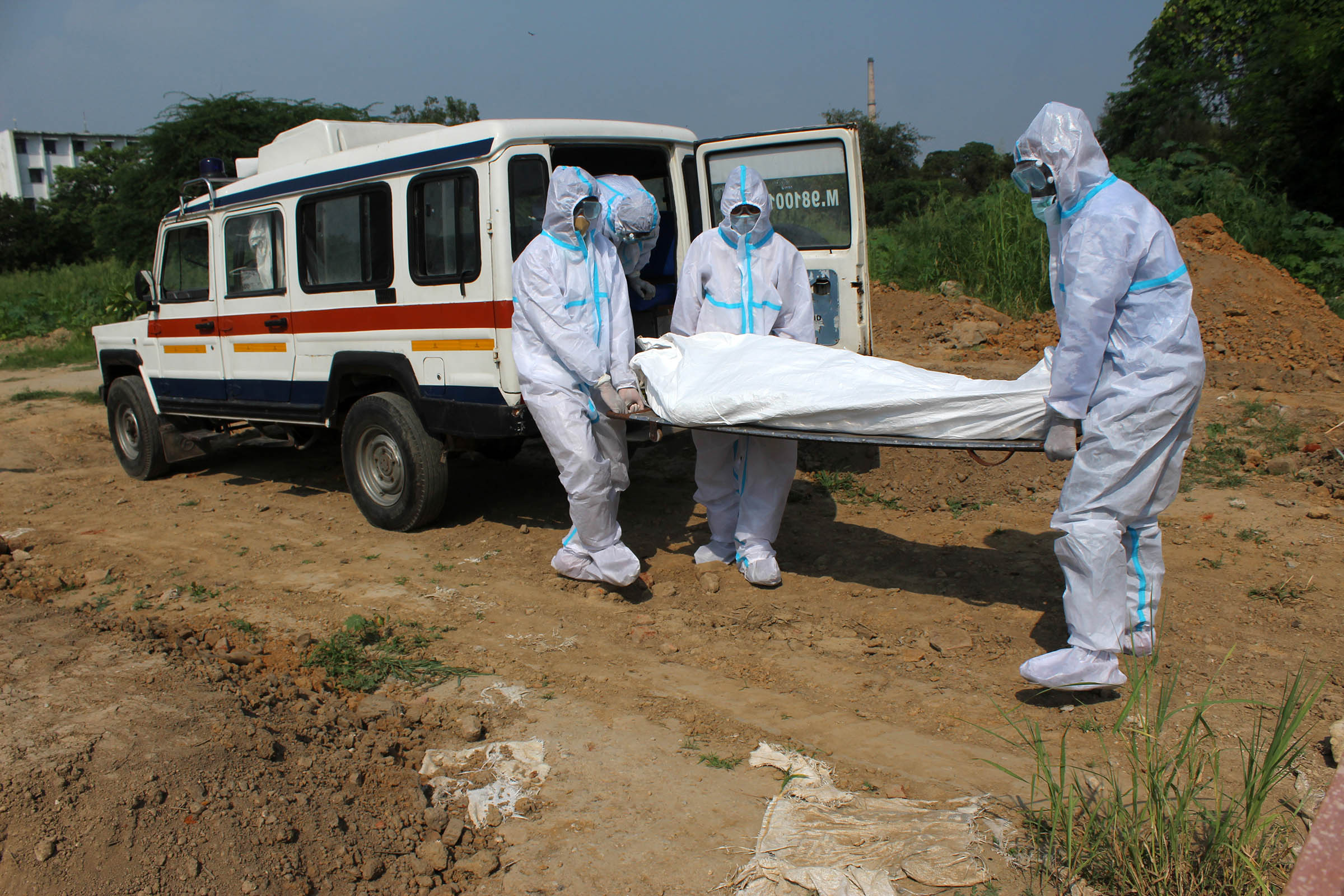 Family members in personal protective equipment (PPE) along with other relatives bury a person who died of COVID-19, at Jadid Qabristan Ahle - Islam graveyard, on September 12, in New Delhi. 