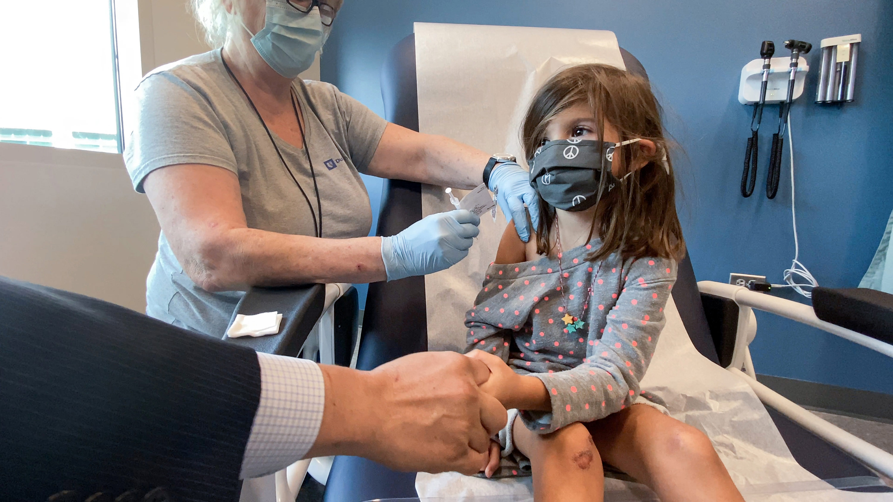 Bridgette Melo, 5, holds onto the hand of her dad Jim Melo as she gets the first of two Pfizer COVID vaccinations on September 28 during a clinical trial for children at Duke Health.
