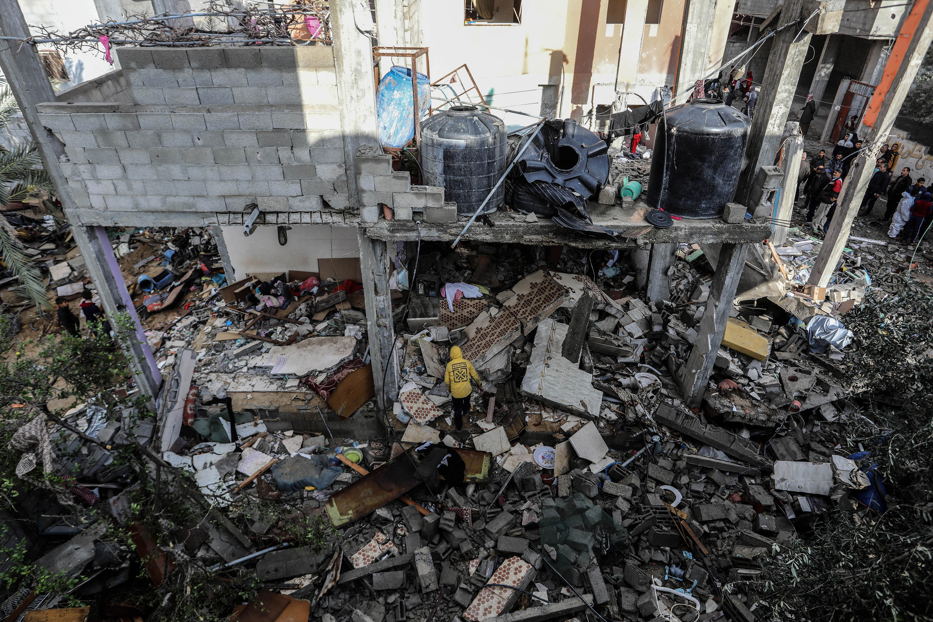 פלסטינים בודקים בית שניזוק לאחר תקיפה אווירית ישראלית על רפיח בדרום עזה ב-27 בינואר.