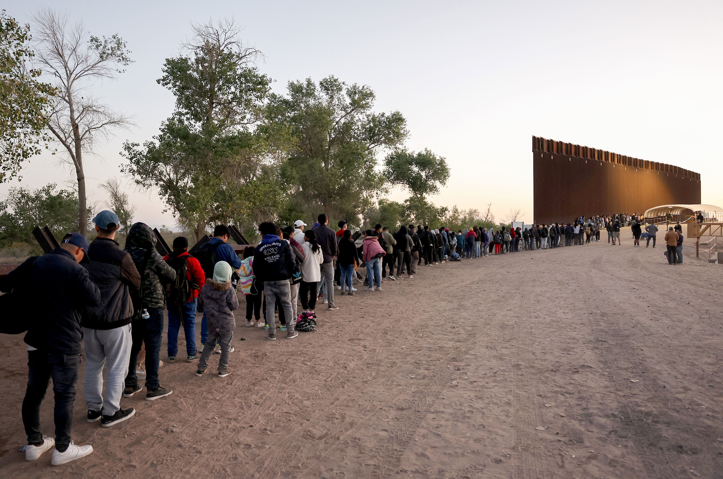Migrants seeking asylum in the United States wait in line to be processed by US Border Patrol agents Thursday after crossing into Yuma, Arizona from Mexico.