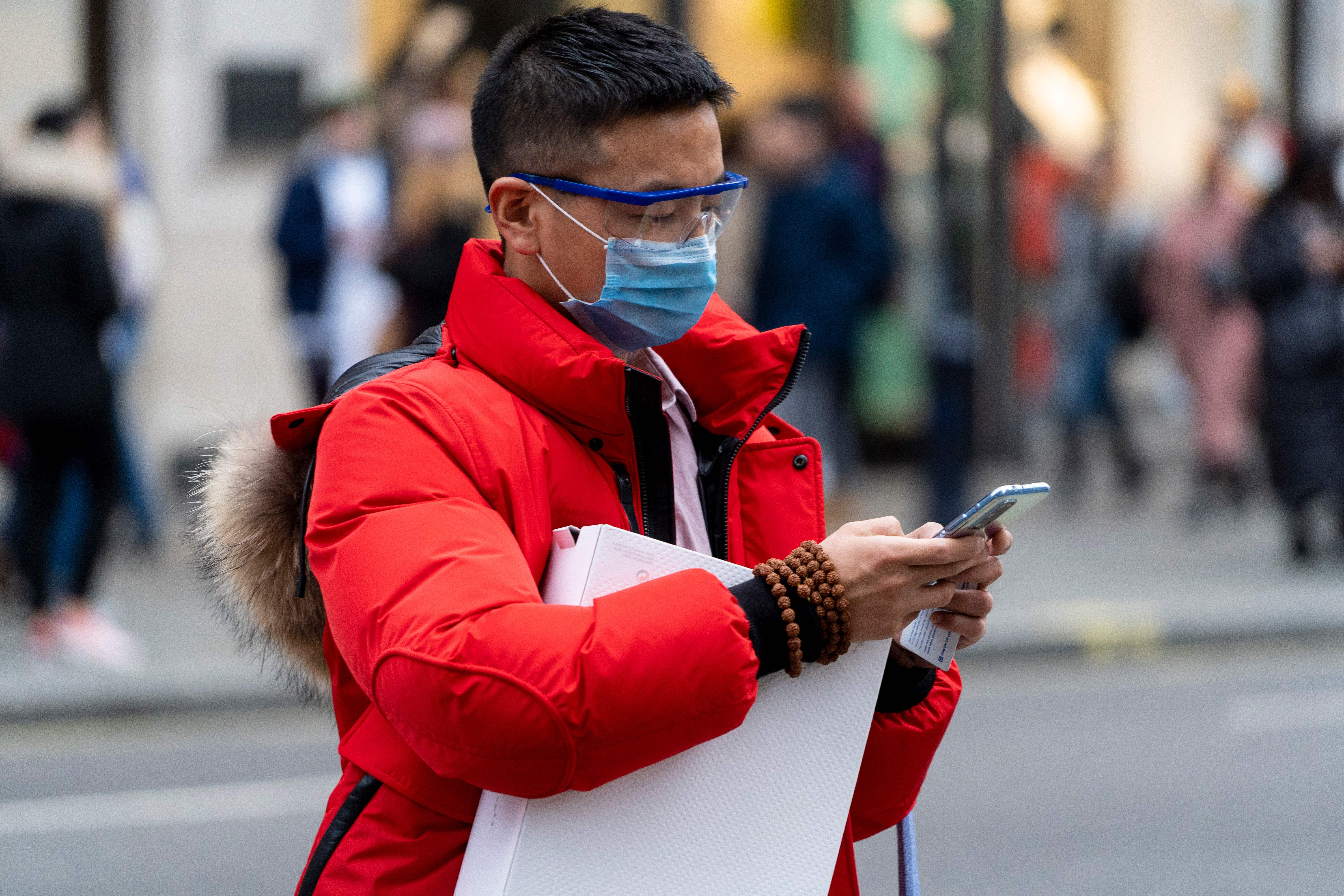 A pedestrian wears a surgical mask as he checks his phone while walking along London's Regent Street in central London on January 25. 