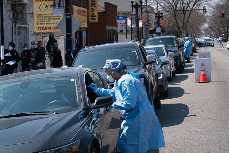 People wait in line in their cars to get tested for COVID-19 at Roseland Community Hospital on April 3 in Chicago.