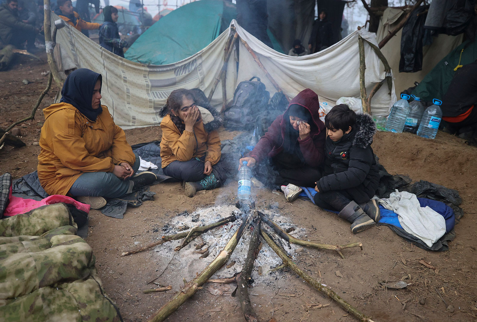 Migrants warm up by a fire at the Poland-Belarus border on Thursday, November 11.
