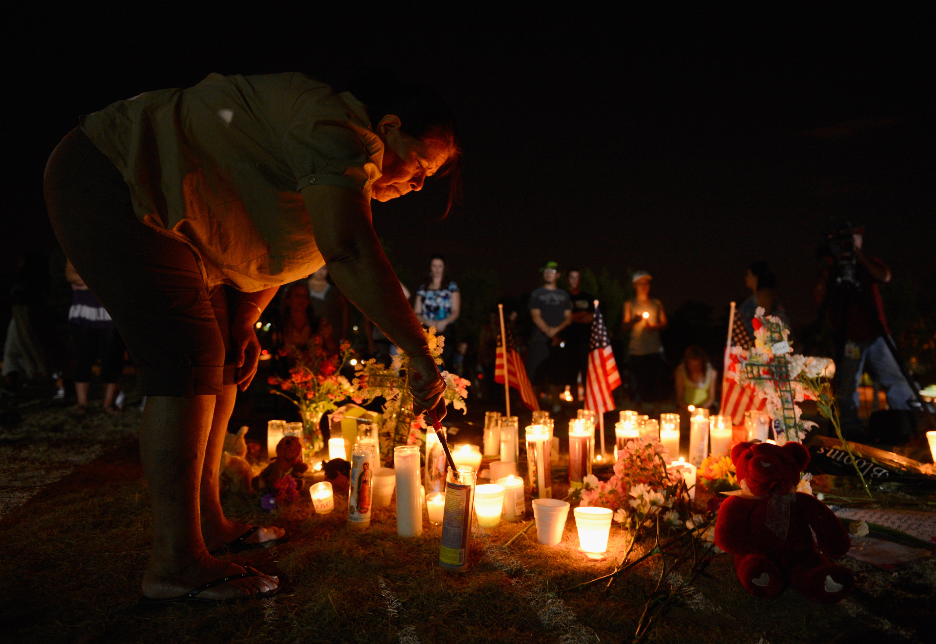 A woman lights candles at a makeshift memorial during a vigil for victims of the Century 16 movie theatre where a gunmen attacked movie goers during an early morning screening of the new Batman movie "The Dark Knight Rises" on July 20, 2012, in Aurora, Colorado. 