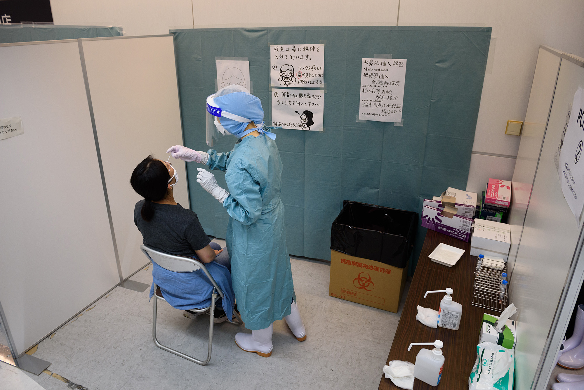 A medical worker in protective gear collects a nasal swab from an arrival passenger to test for Covid-19 at a polymerase chain reaction (PCR) testing site inside Narita Airport in Narita, Japan, on Sunday, July 19. 