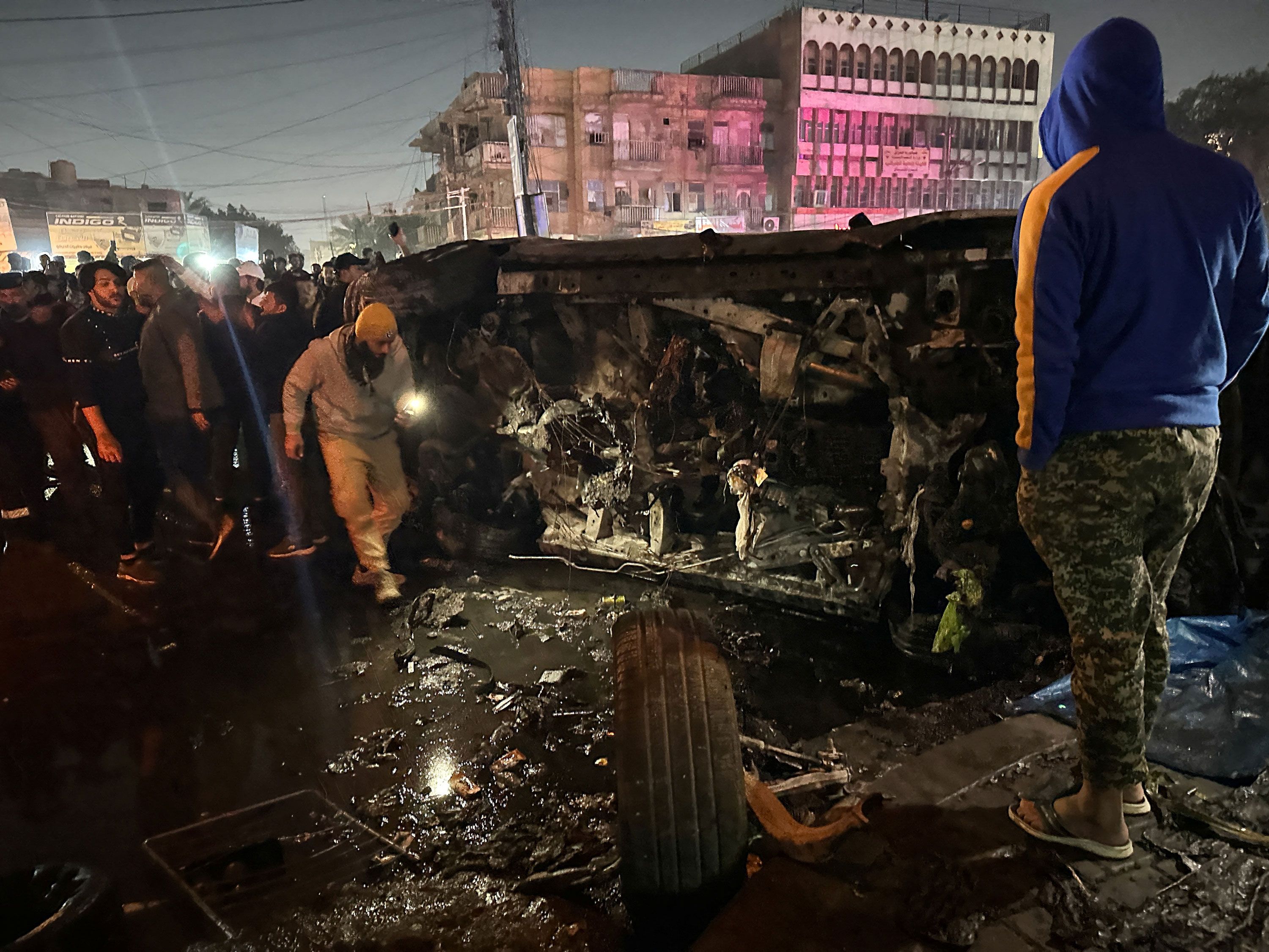 La gente inspecciona un vehículo después de lo que fuentes de seguridad dijeron que fue un ataque mortal con aviones no tripulados, en Bagdad, Irak, el 7 de febrero.