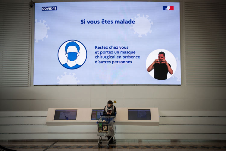 A woman stands under a public health message in a shopping center in Saint-Herblain, France, on March 13. 