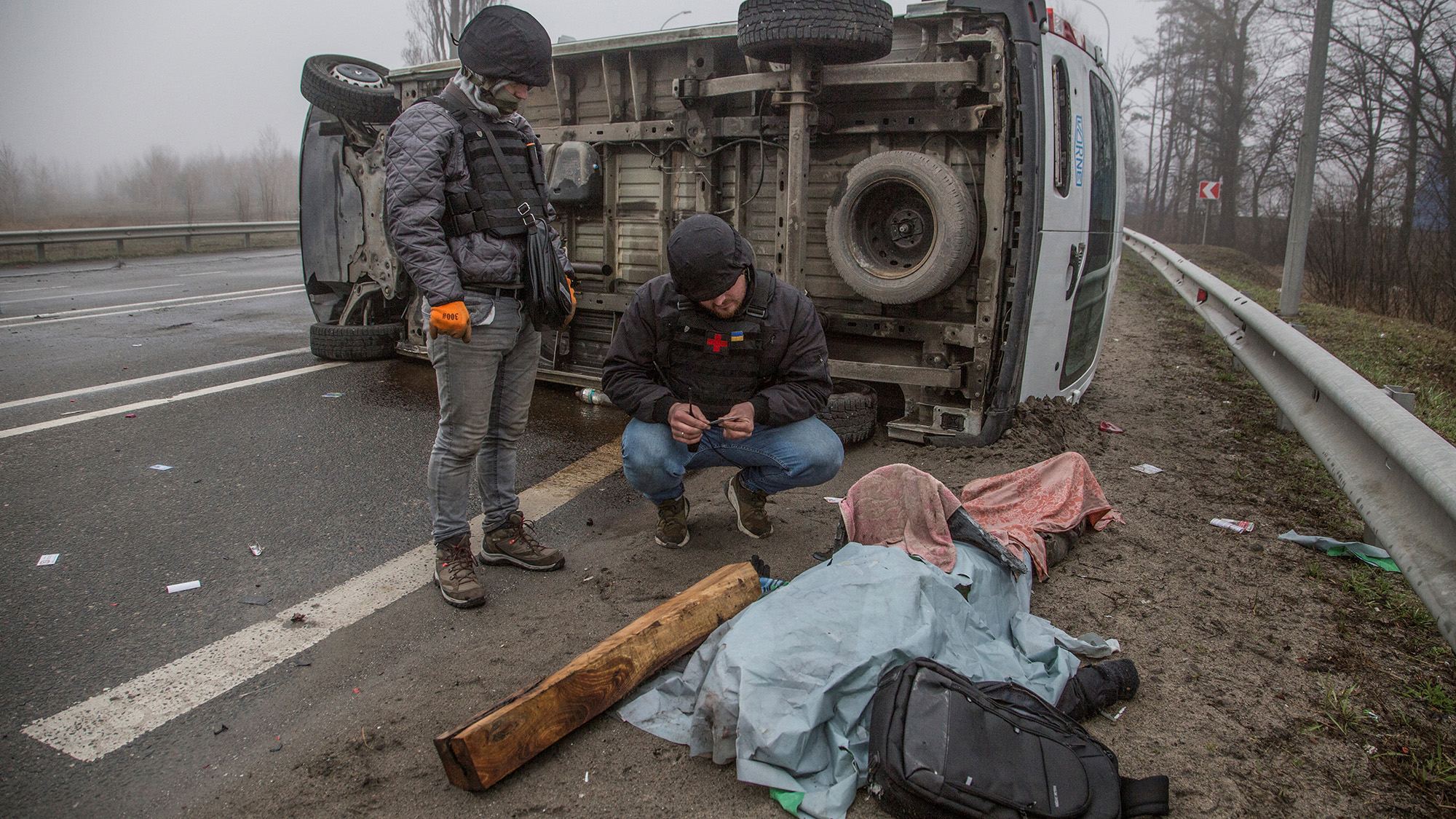 Volunteers inspect a body left on a street in Bucha, Ukraine on April 1.