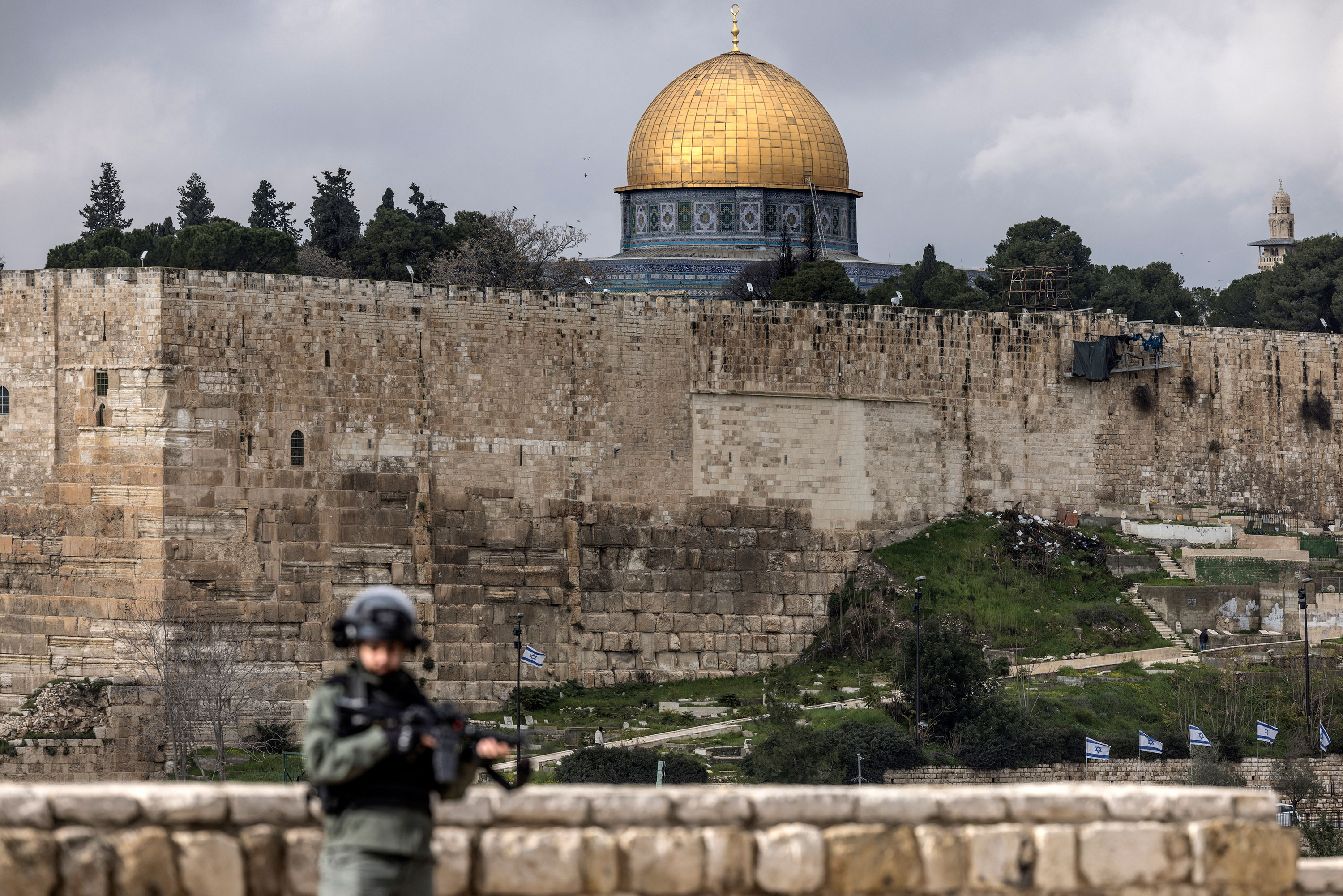 The Dome of the Rock, in the al-Aqsa mosque compound, is seen in the distance as an Israeli soldier stands guard during Friday noon prayer along a street in the east Jerusalem neighborhood of Ras al-Amud, on January 26. 