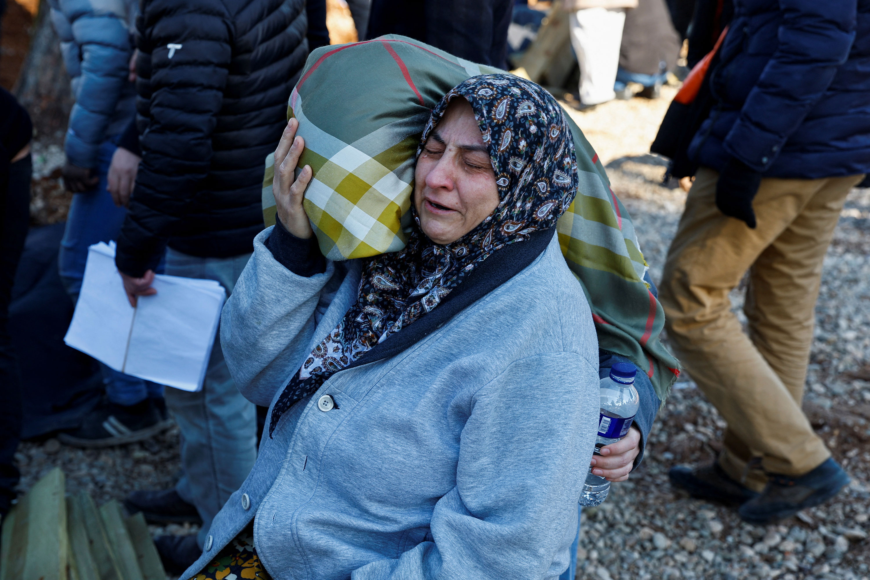 A woman reacts as people bury victims of the deadly earthquake in a cemetery in Kahramanmaras, Turkey, on February 9. 