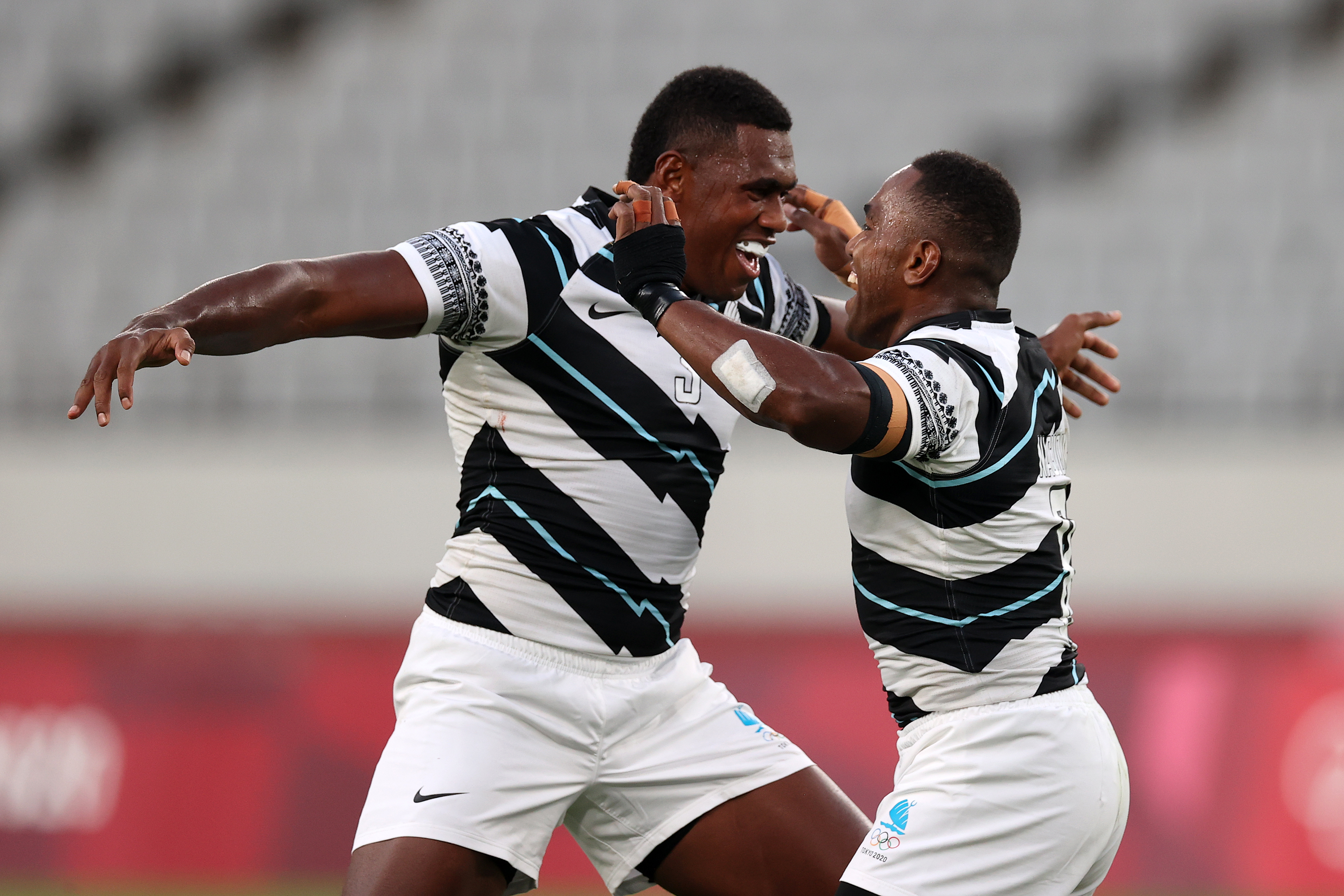 Rugby players Kalione Nasoko, left, and Waisea Nacuqu of Fiji celebrate their victory against New Zealand during the gold medal match on July 28.