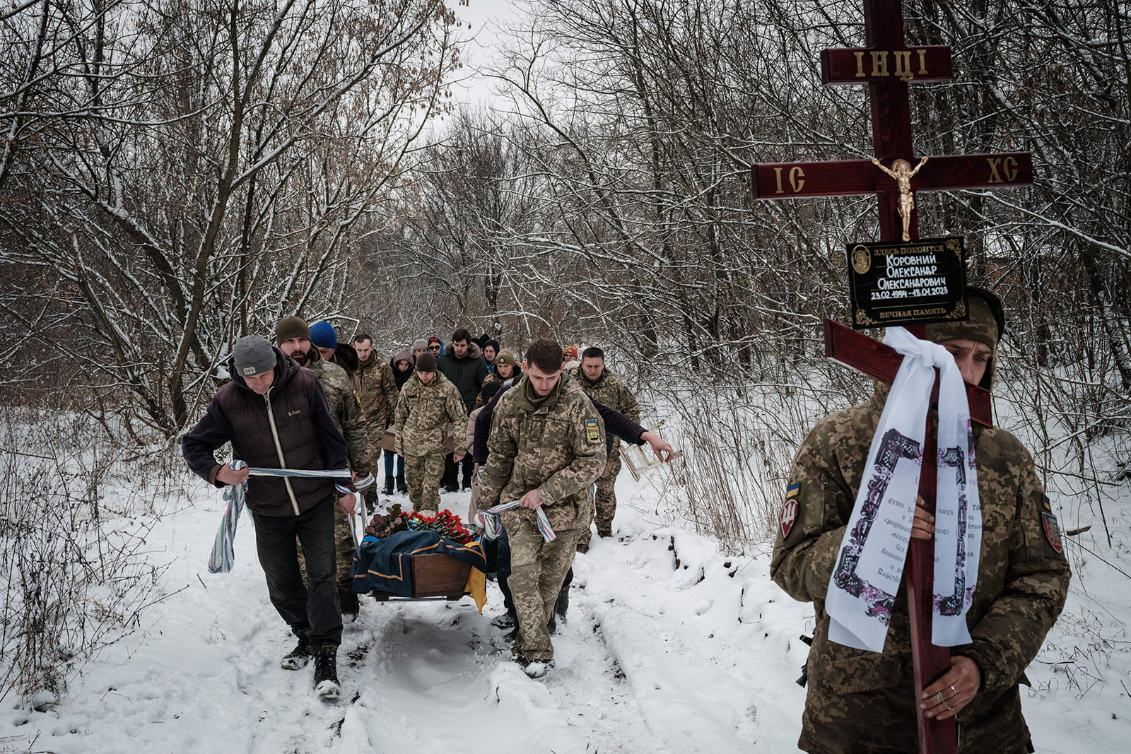 Oleksiy Storozh, right, 28, carries a cross to be placed at the grave of his late best friend, Ukrainian serviceman of the Azov Battalion Oleksandr Korovniy, 28, who was killed in action in Bakhmut, as friends carry Korovniy's coffin to a cemetery in Sloviansk on January 30. 