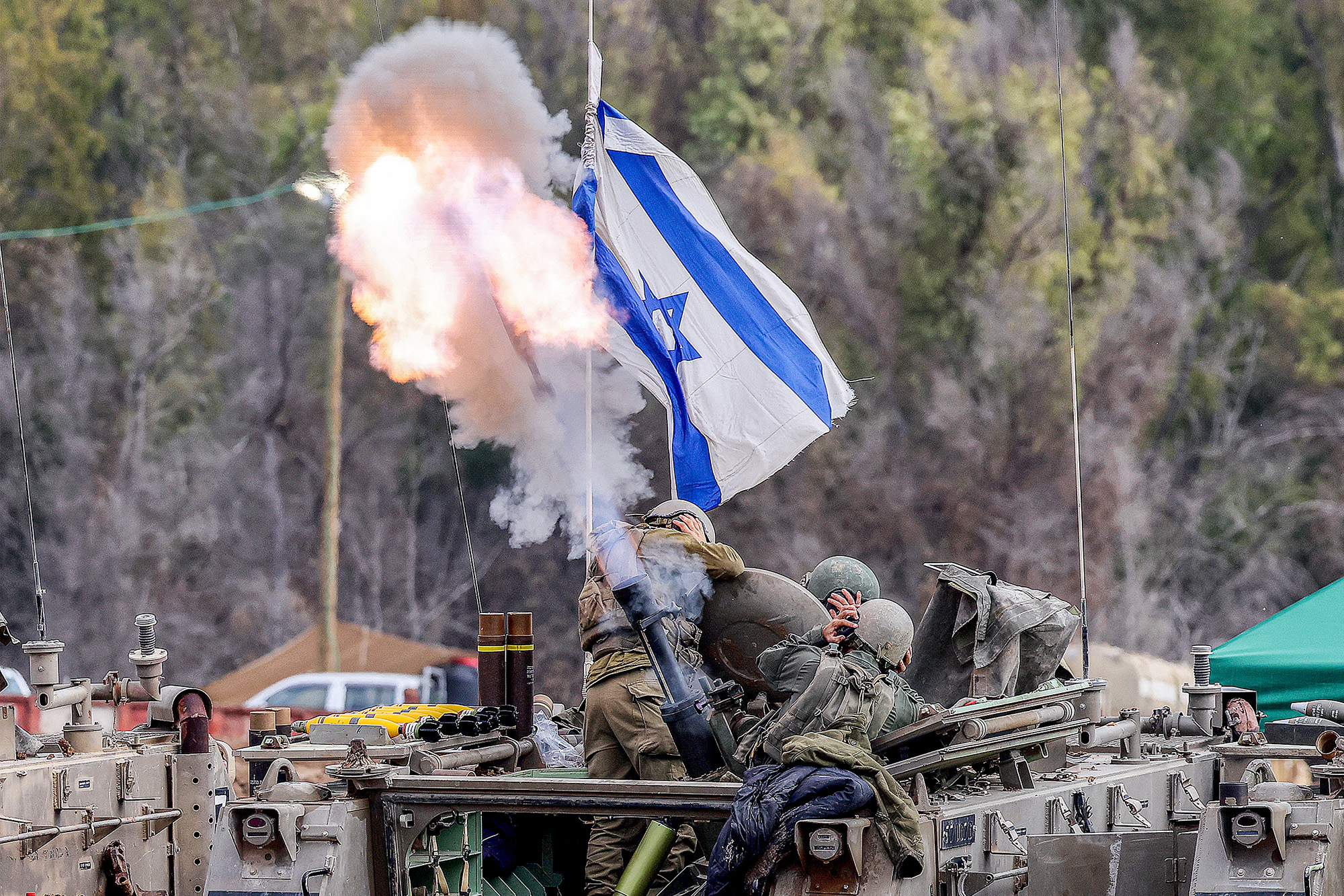 Israeli soldiers cover their ears as they a fire mortar round from an armoured vehicle at a position along the border in southern Israel on January 3.