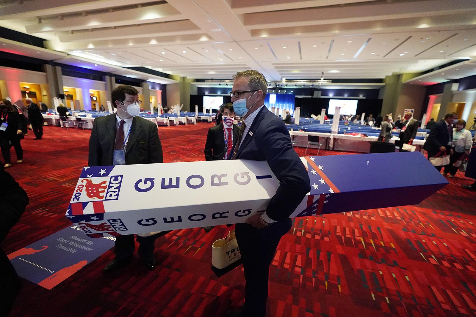 A member of the Georgia delegation walks out with their delegation placard after the vote on the first day of the Republican National Convention, Monday, August 24, in Charlotte.