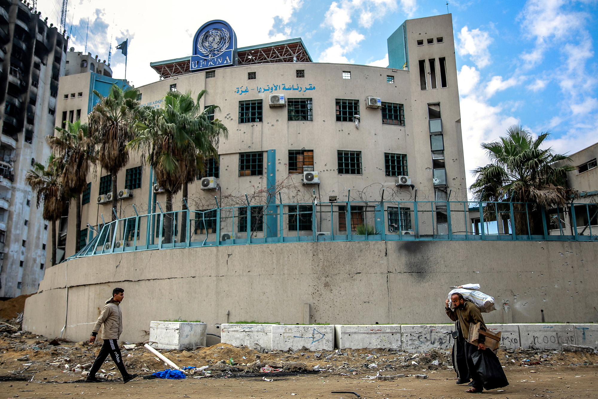 People walk past the damaged Gaza City headquarters of the United Nations Relief and Works Agency for Palestine Refugees (UNRWA) on February 15.