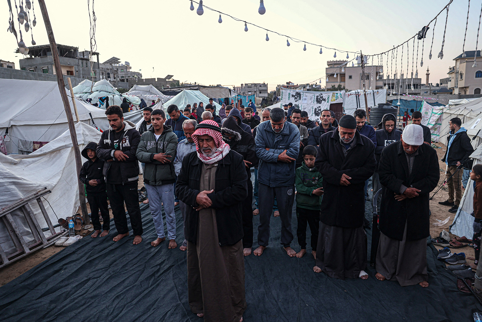 Palestinians pray before breaking the fast on the first day of the Islamic holy month of Ramadan at a camp for displaced people in Rafah, Gaza's southern city, on March 11.