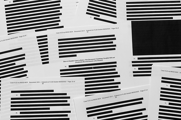 Pages of the FBI affidavit in support of obtaining a search warrant for former President Donald Trump's Mar-a-Lago property are photographed showing large redacted portions. 